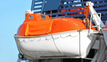 Orange enclosed lifeboat secured on a vessel’s davits
